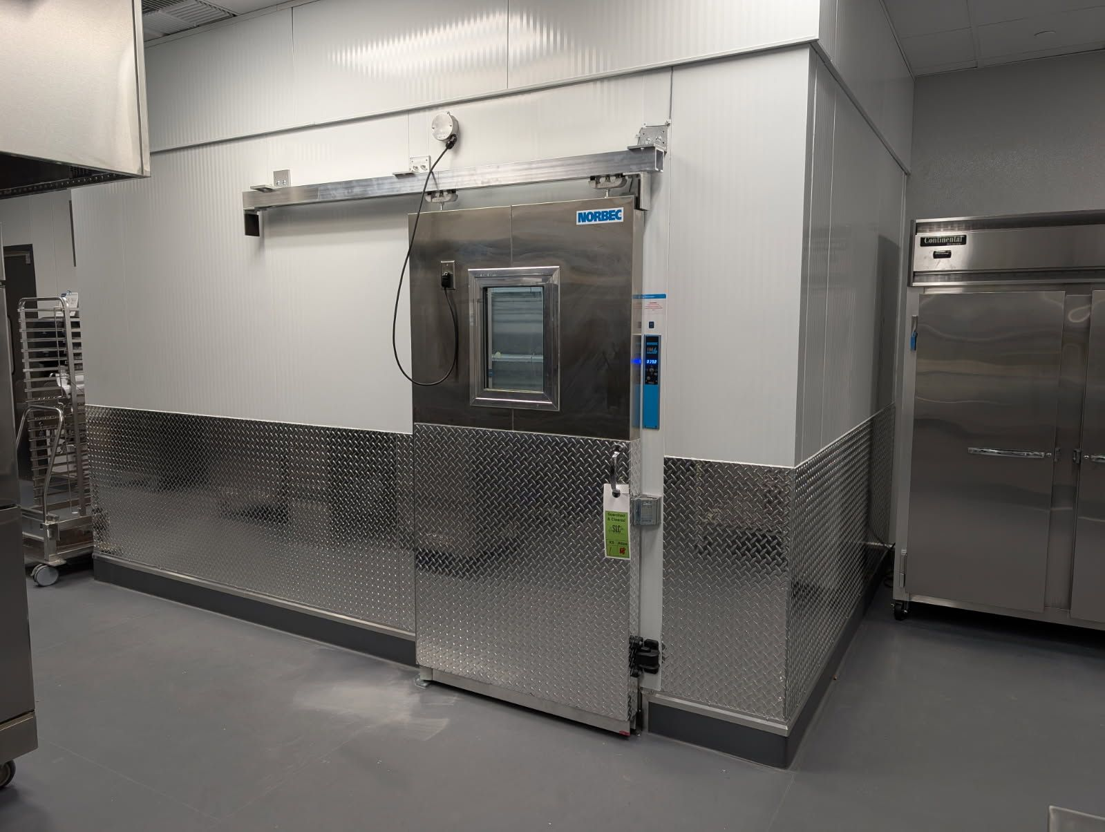 Touchstone Refrigeration commercial walk-in installation with stainless steel door, NORBEC panels, and diamond-plate kick guards